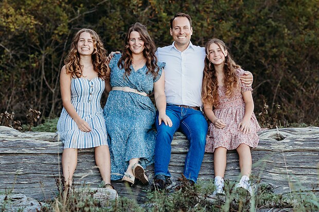 Adam Walker with his wife and two daughters on a driftwood log